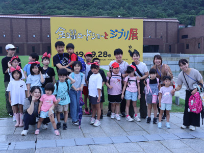看板の前で幼稚部・小学部全員で集合写真を撮っている様子